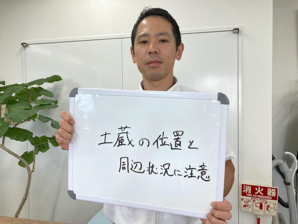 土蔵の解体費用について解説するホワイトボードを持つ初田さん