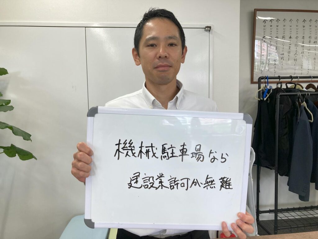 機械式駐車場について解説し、ホワイトボードを持つ初田理事