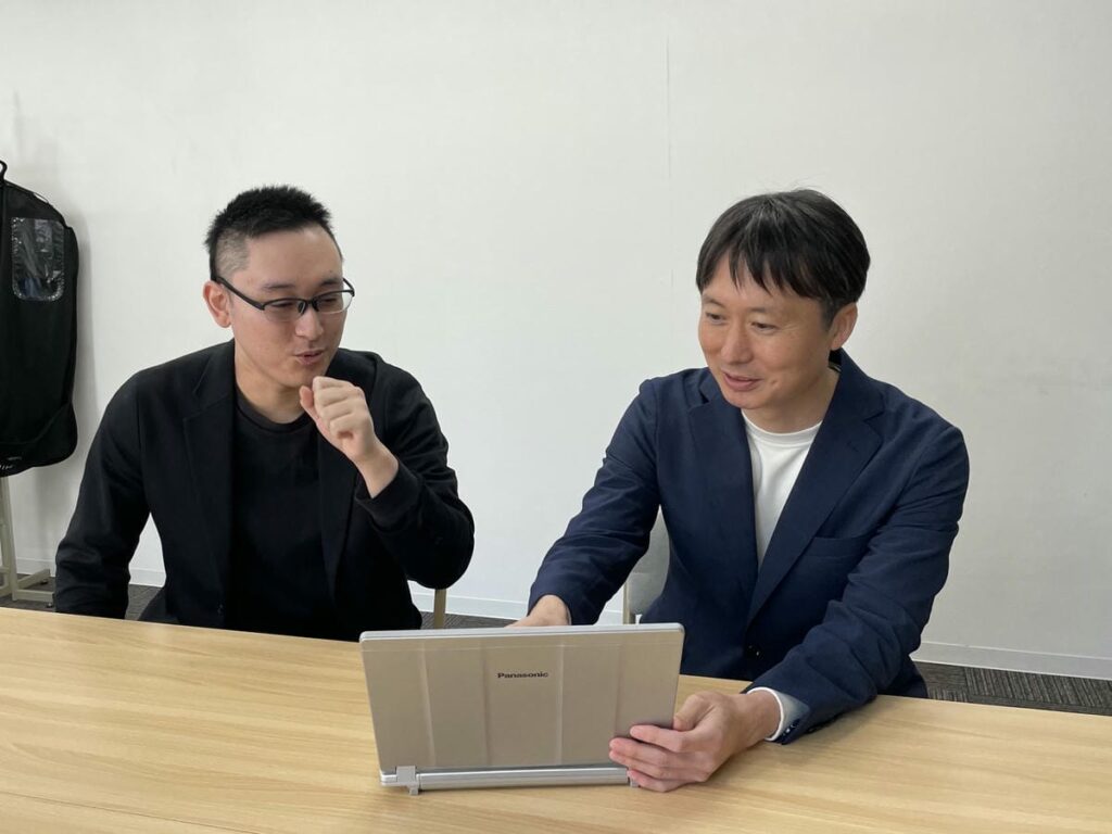 稲垣に中野理事がノートパソコンを使って説明している様子