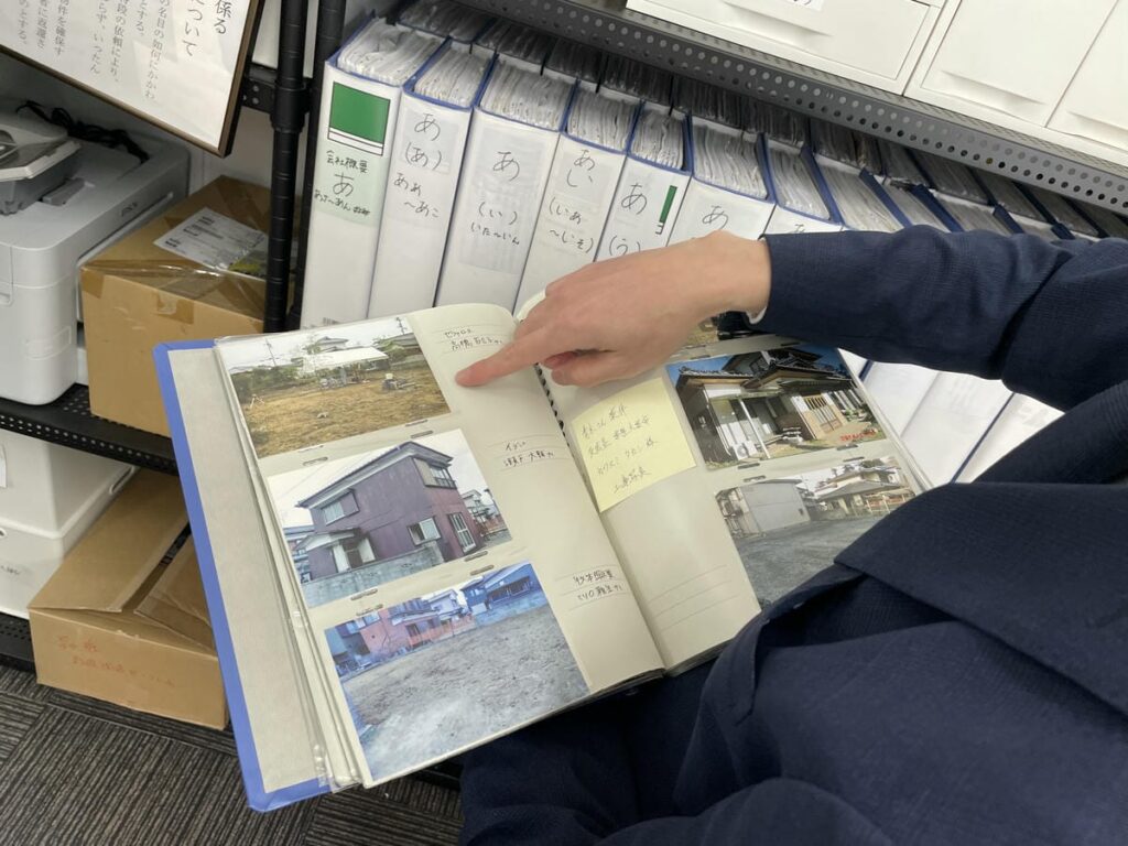 ファイルを広げ、解体現場写真を指差す中野理事