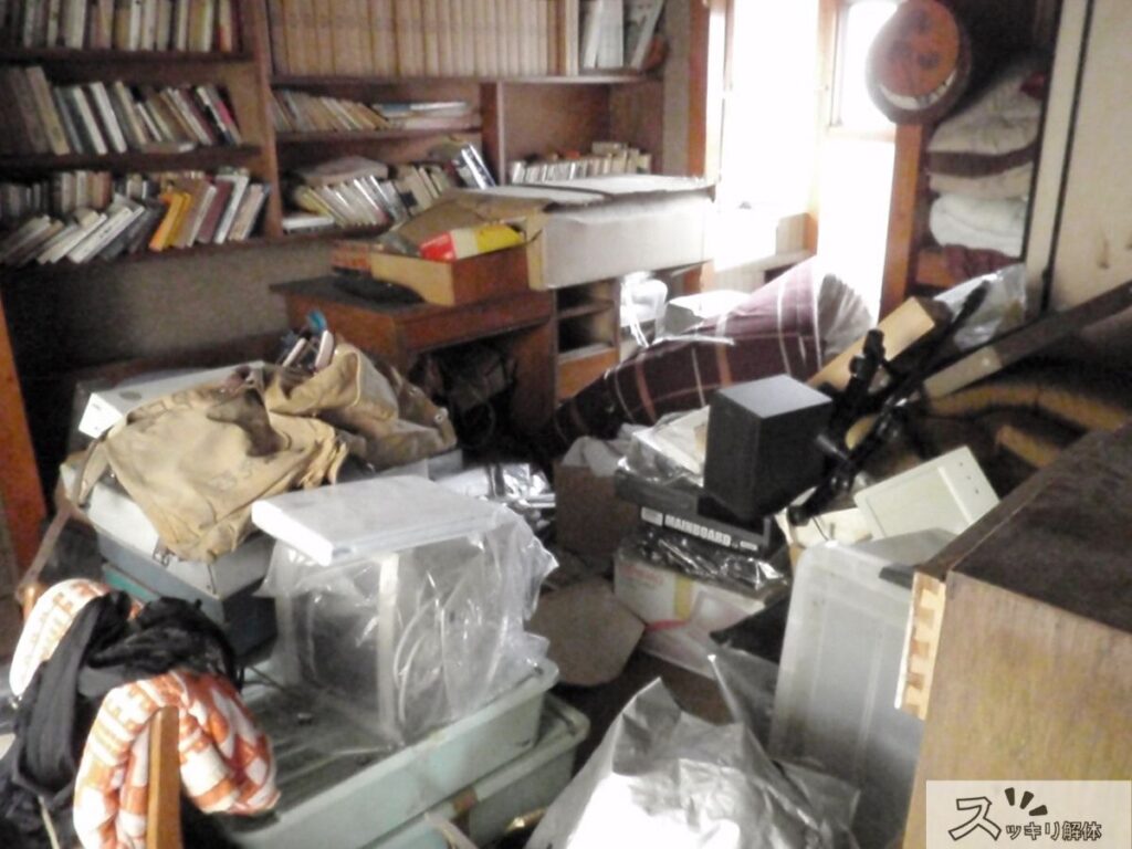大量の書籍や衣類が散乱した室内の様子