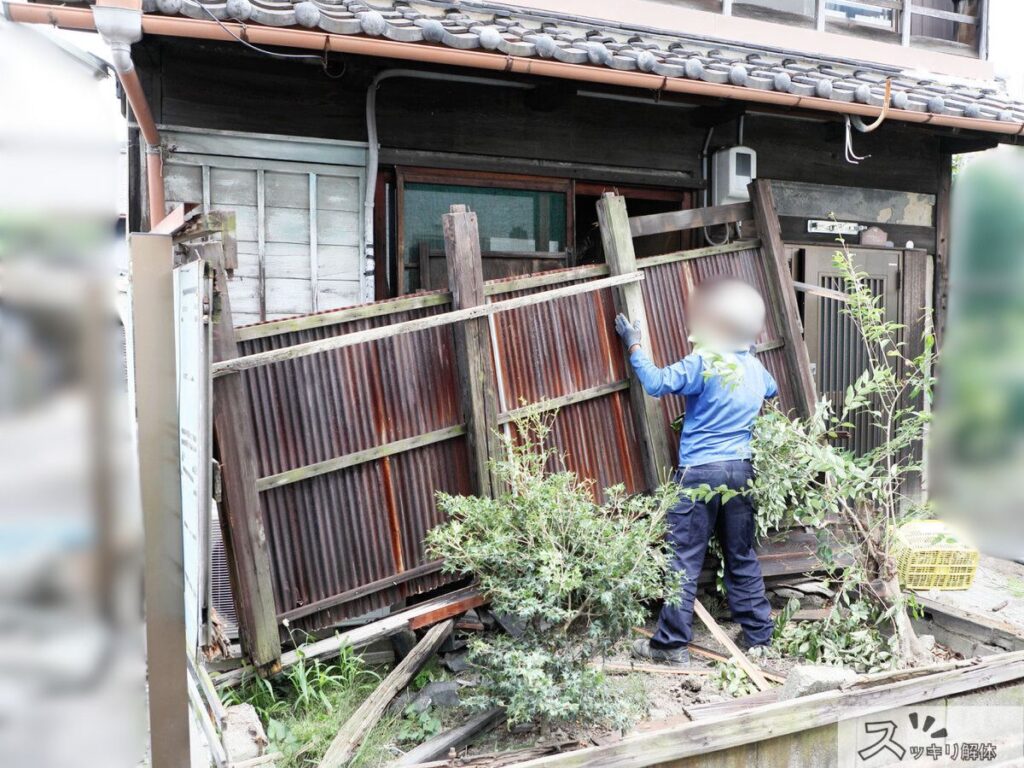 空き家の外装材や付随する木製の構造物を手作業で解体・撤去している様子