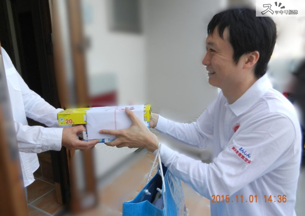 解体工事の着工前に、業者が近隣住民へ粗品を渡して挨拶をしている様子。