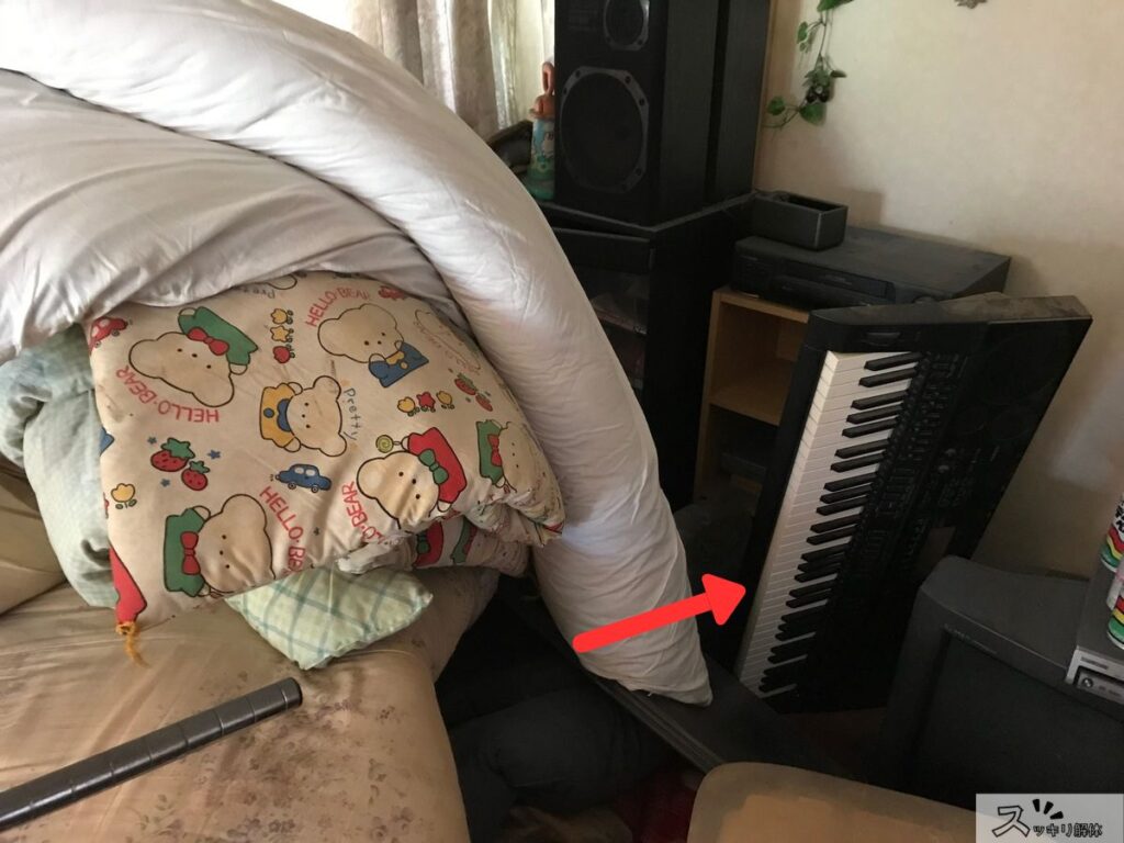搬出待ちの不用品に囲まれた電子ピアノ。他の家電や寝具と一緒に処分しやすい例